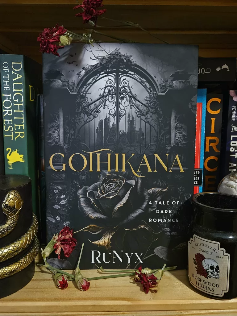 photo of 'Gothikana' book cover with gothic gates and dark rose, surrounded by flowers and themed decor